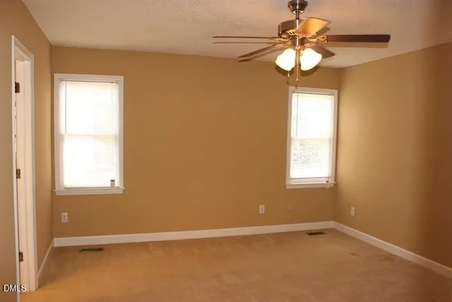 an empty room with windows and chandelier fan