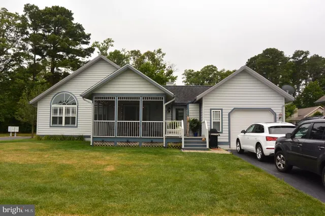 a view of a white house with a big yard and large trees