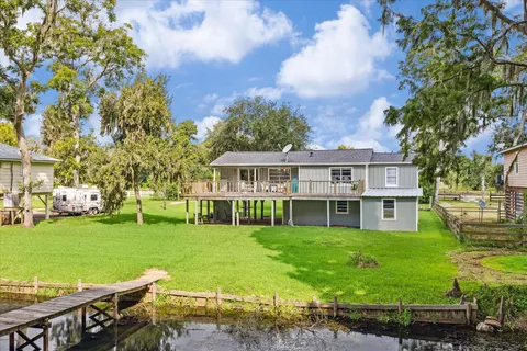 a view of a house next to a big yard with plants and large trees