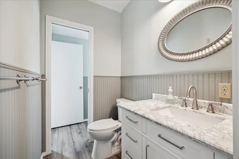 a bathroom with a granite countertop toilet a sink and a mirror