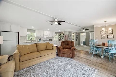 a living room with furniture kitchen view and a wooden floor