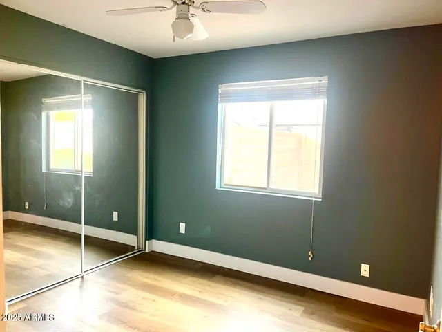 a view of an empty room with window and wooden floor