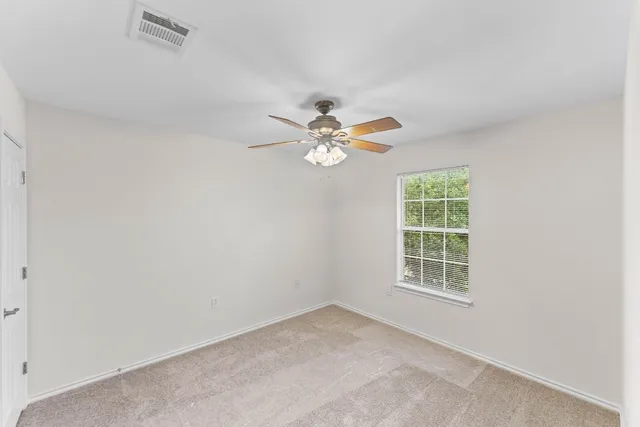 an empty room with window and ceiling fan