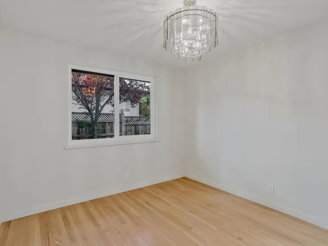 a view of empty room with wooden floor and window