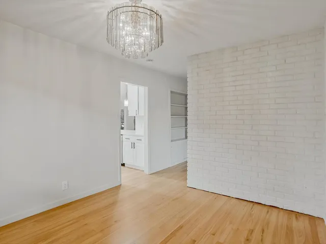 a view of empty room with wooden floor and chandelier