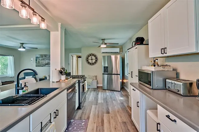 a kitchen with stainless steel appliances granite countertop a refrigerator a stove a sink dishwasher and wooden cabinets with wooden floor