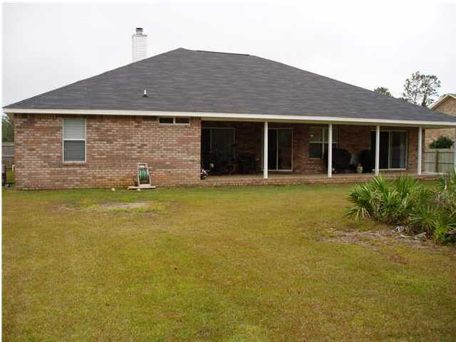 6894 Fernandina Road Navarre, FL 32566 - Photo 16 of 17 a front view of a house with a yard and potted plants