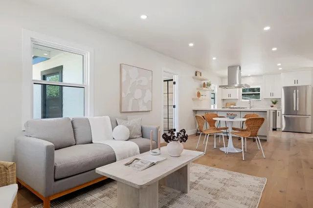 a living room kitchen with furniture and a dining table with wooden floor