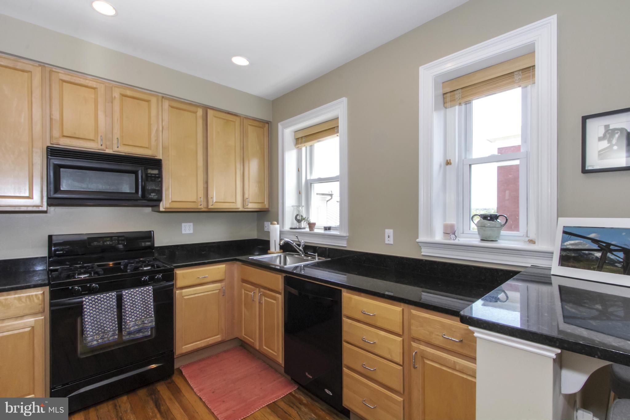 1423 R Street Northwest, Unit 505 Washington, DC 20009 - Photo 10 of 22 a kitchen with granite countertop white cabinets sink and stainless steel appliances