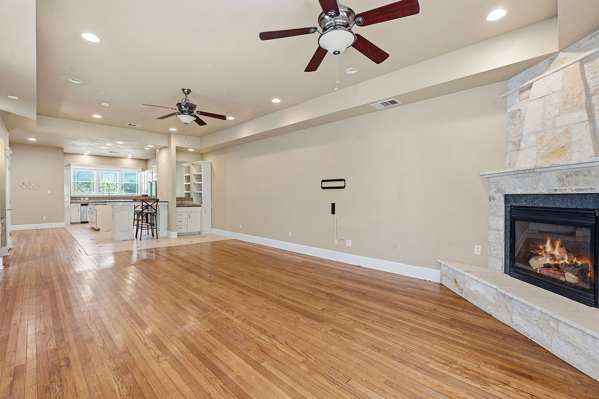 1305 Cometa Street Austin, TX 78721 - Photo 4 of 28 A spacious living area flows into the kitchen, featuring rich hardwood flooring and a warming fireplace.