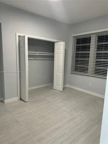 a view of empty room with wooden floor and window