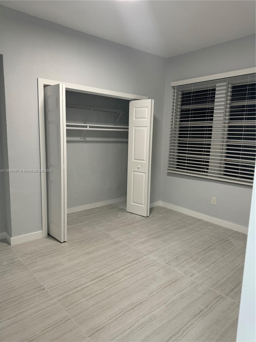 1101 Northwest 32nd Place, Unit MIDDLE Miami, FL 33125 - Photo 6 of 8 a view of empty room with wooden floor and window