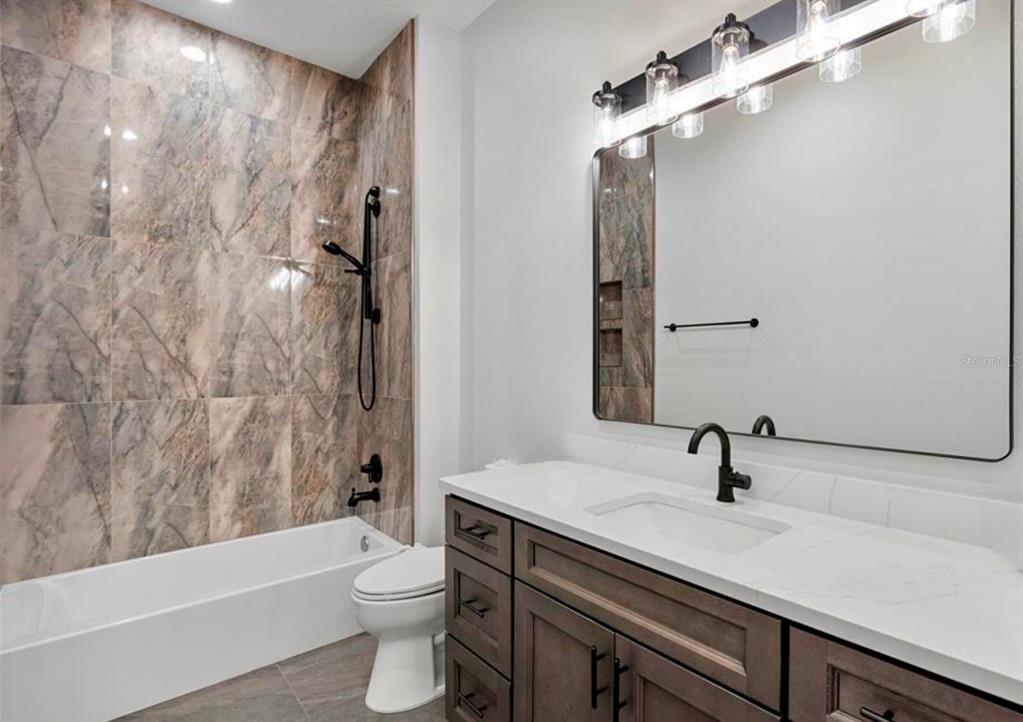 224 Valencia Ridge Drive Auburndale, FL 33823 - Photo 25 of 39 a bathroom with a sink a toilet a mirror a bathtub and shower