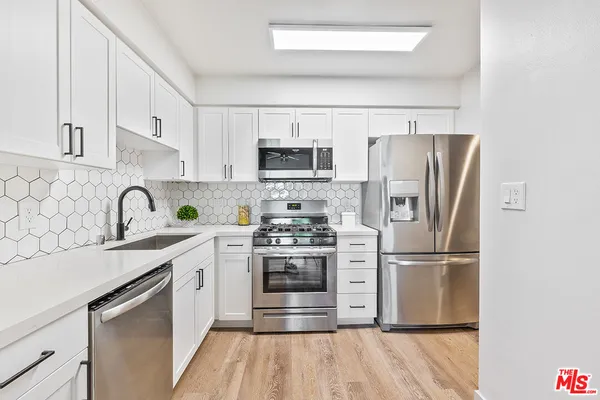 a kitchen with stainless steel appliances a refrigerator sink and microwave