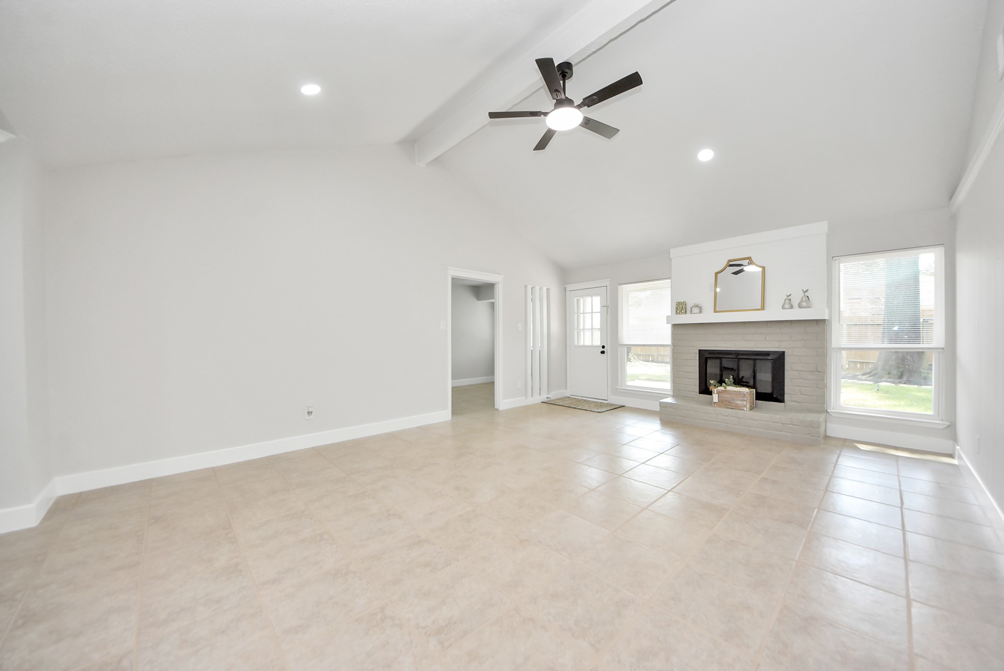 5314 Sweetwind Lane Spring, TX 77373 - Photo 28 of 47 Living room with high ceilings, modern ceiling fan, and abundant natural light. The cozy fireplace is flanked by two windows, creating a bright and inviting atmosphere.