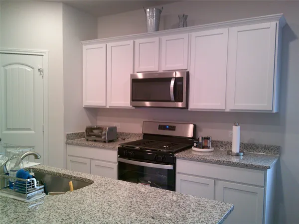 a kitchen with granite countertop a sink a stove and cabinets