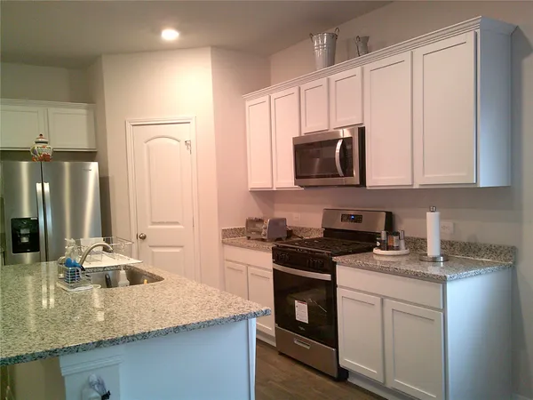 a kitchen with stainless steel appliances granite countertop a sink a stove and a refrigerator