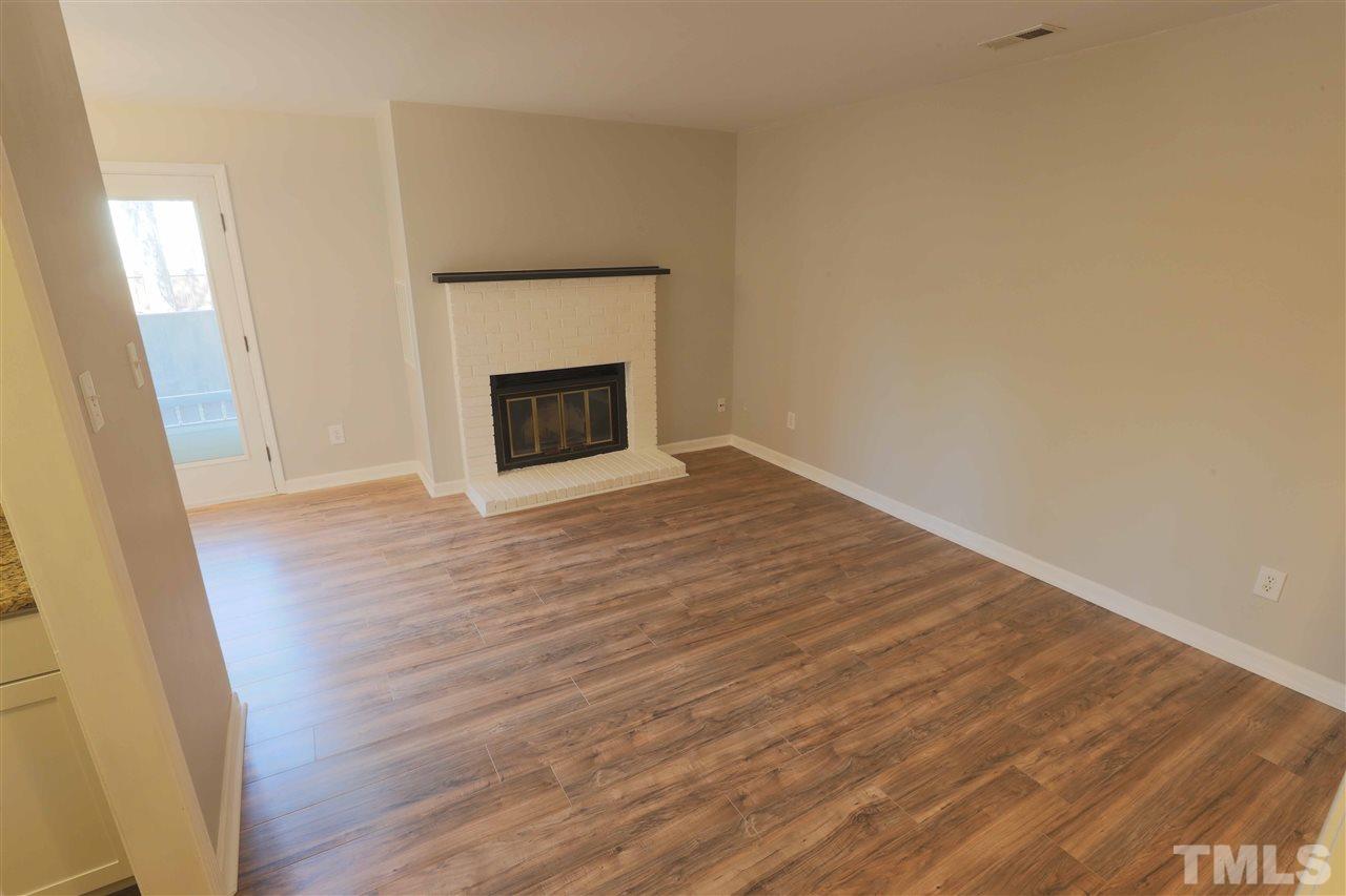3533 Mill Run, Unit N/A Raleigh, NC 27612 - Photo 4 of 19 a view of empty room with wooden floor and fireplace