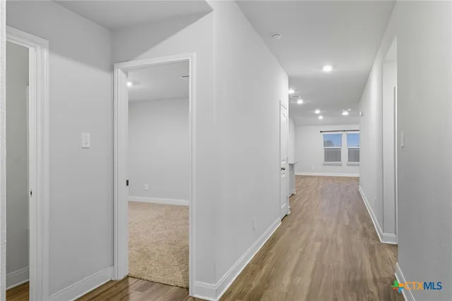 a kitchen with stainless steel appliances granite countertop a refrigerator a sink dishwasher a stove top oven a refrigerator and white cabinets with wooden floor