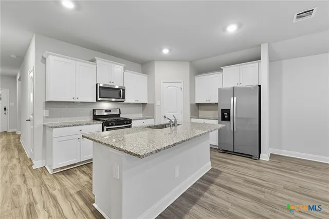 a kitchen with granite countertop white cabinets and sink