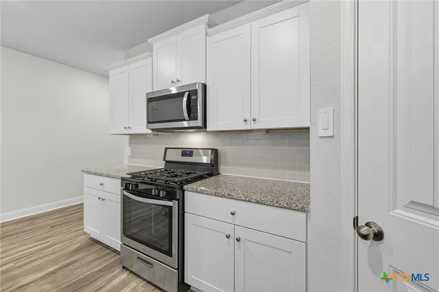a kitchen with granite countertop a refrigerator and cabinets