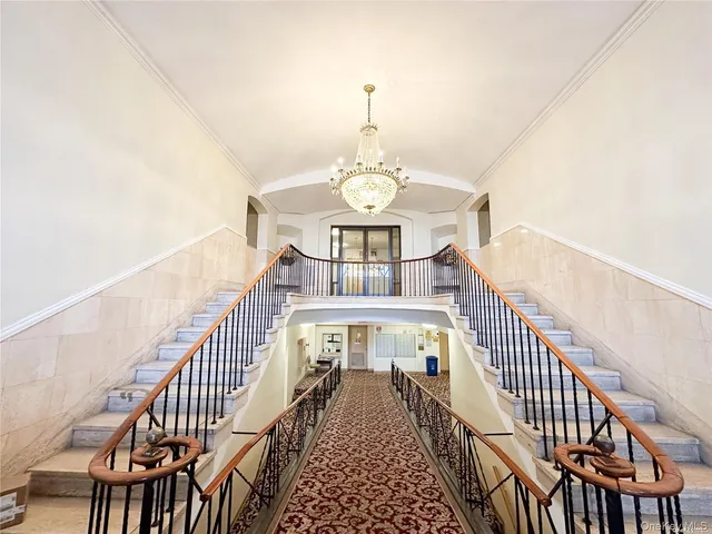 a view of staircase with lots of frames on wall and a chandelier