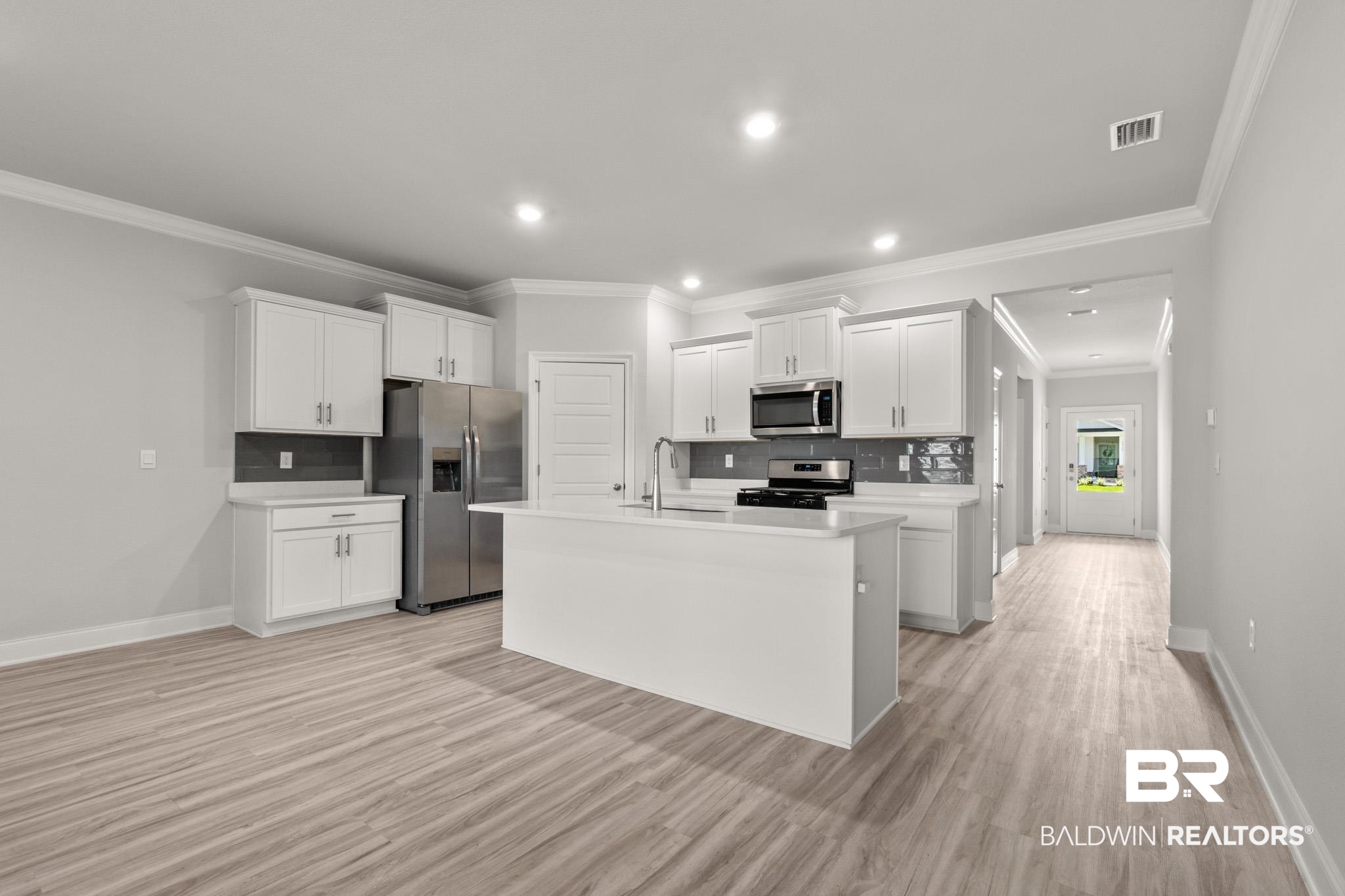 32125 Lyon Road Daphne, AL 36527 - Photo 6 of 70 Spacious kitchen featuring white cabinetry, a large island with a sink, stainless steel appliances, and wood-finish flooring