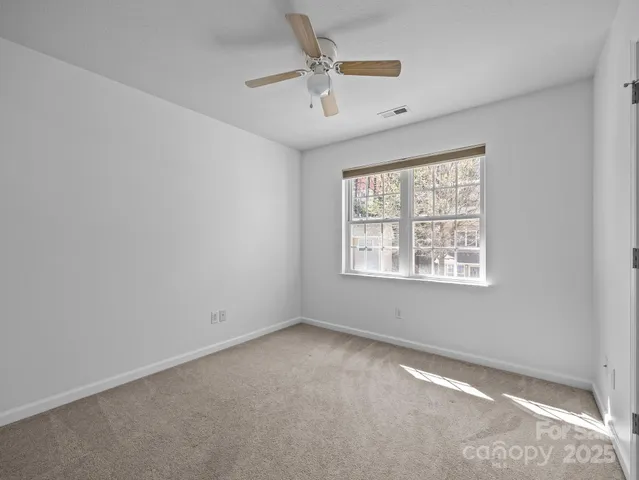 an empty room with windows and ceiling fan