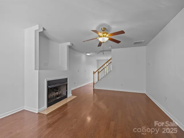 a view of an empty room with wooden floor and a fireplace