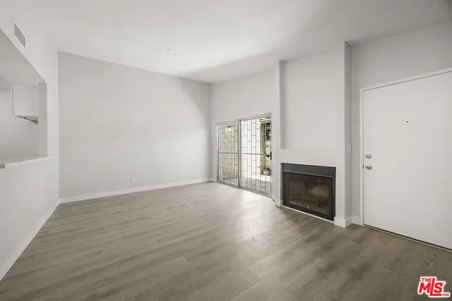 a view of empty room with wooden floor and fireplace