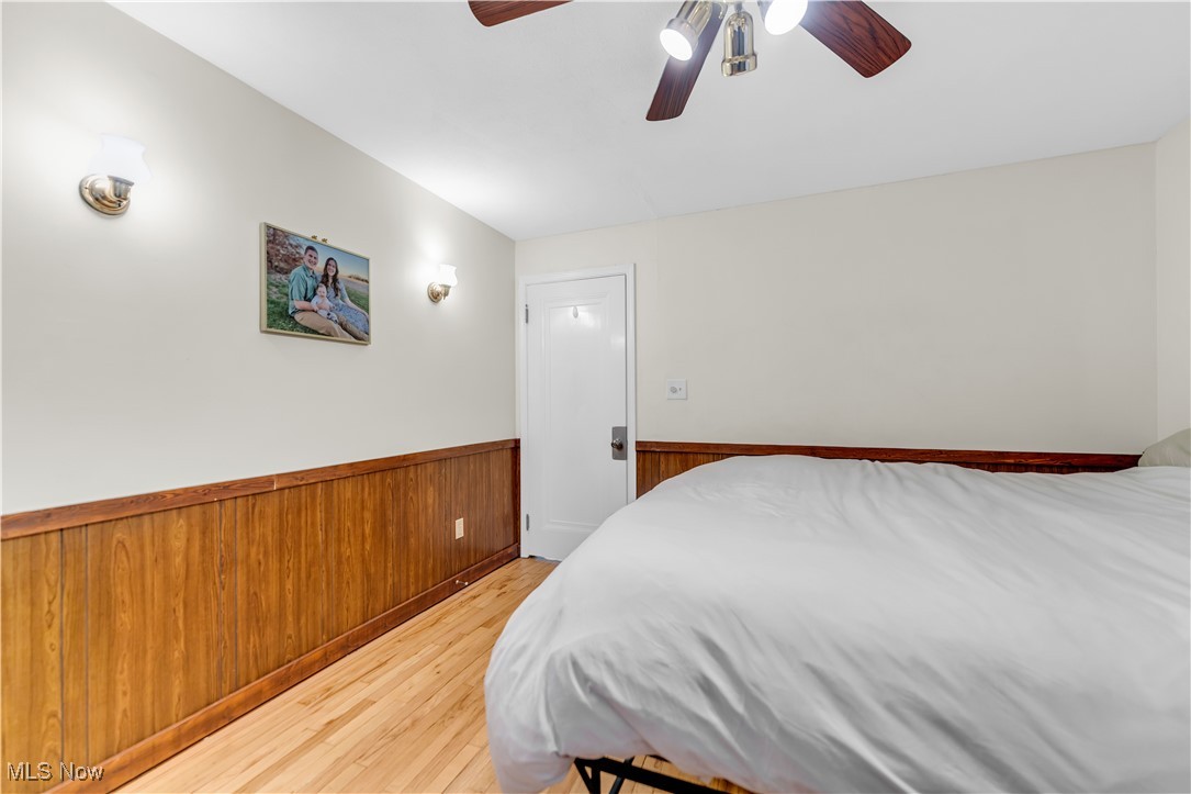 3729 Grosvenor Road Cleveland, OH 44118 - Photo 30 of 39 Bedroom featuring a wainscoted wall, wooden walls, ceiling fan, and light wood finished floors
