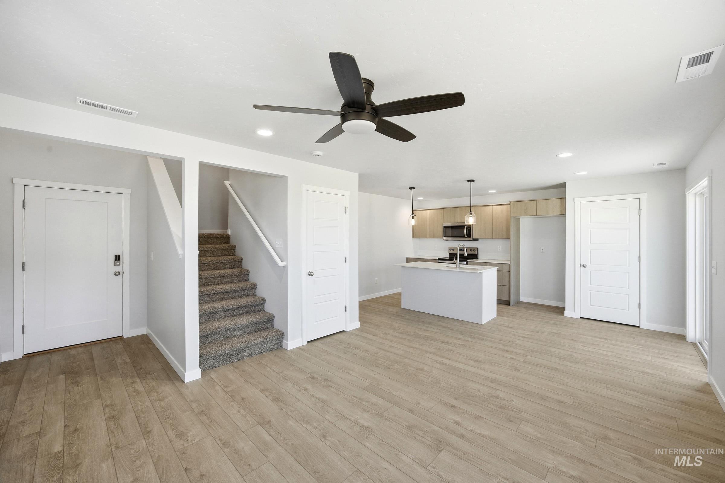 16211 Andes Avenue Caldwell, ID 83607 - Photo 10 of 22 Open-concept living area featuring wood-finish flooring, a contemporary kitchen with light cabinetry, a central island, and stainless steel appliances