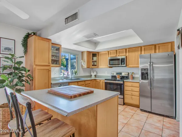 a kitchen with stainless steel appliances granite countertop a refrigerator a stove a sink a dining table and chairs