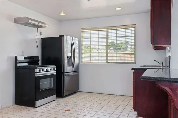 a kitchen with stainless steel appliances granite countertop a refrigerator a stove a sink and a window
