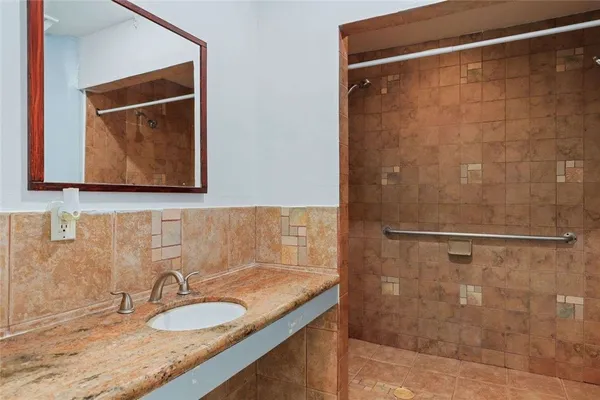 a bathroom with a granite countertop sink mirror and shower