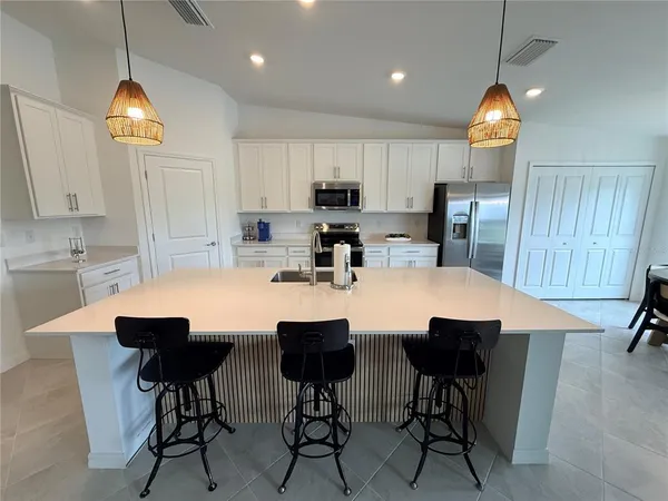 a kitchen with stainless steel appliances granite countertop a dining table chairs sink refrigerator and cabinets