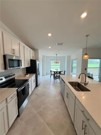a kitchen with kitchen island granite countertop a sink counter top space appliances and cabinets