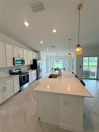 a large kitchen with kitchen island a stove a sink a center island and a wooden floor