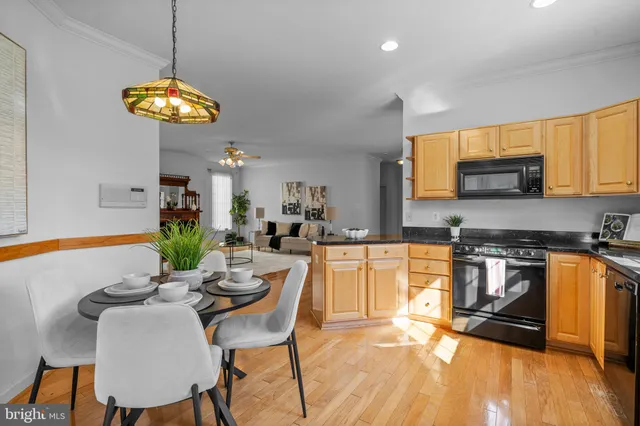 a kitchen with stainless steel appliances granite countertop a stove a sink a microwave a dining table and chairs with wooden floor