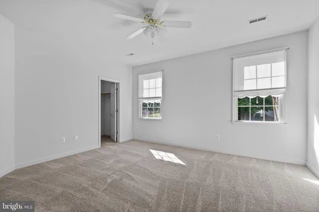 an empty room with windows and fan