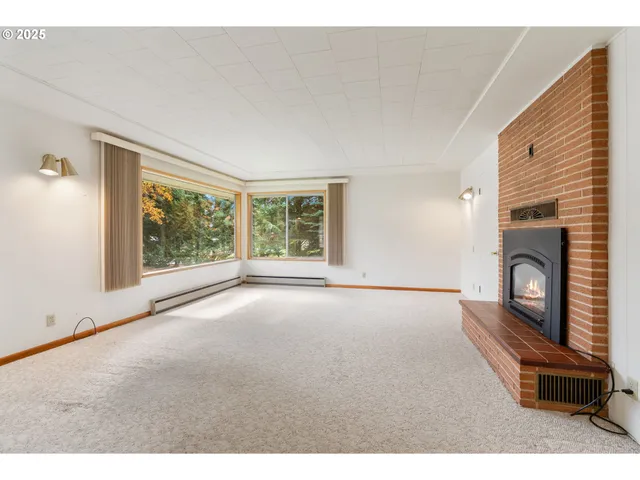 a view of an empty room with a window and fireplace