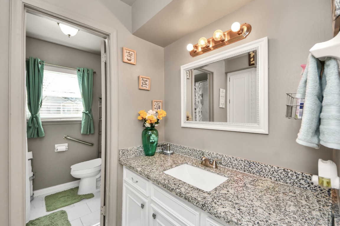 1805 9th Street Hempstead, TX 77445 - Photo 20 of 35 a bathroom with a granite countertop sink a toilet and a mirror