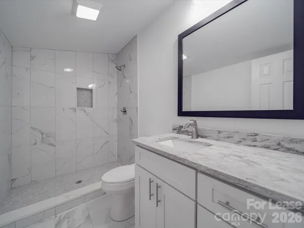a bathroom with a granite countertop sink a toilet and shower