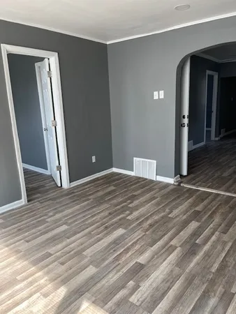 an empty room with wooden floor and entrance