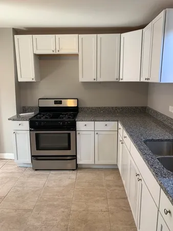 a kitchen with granite countertop a stove a sink and cabinets