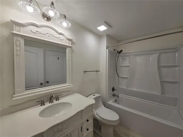 a bathroom with a granite countertop sink a toilet a mirror and shower