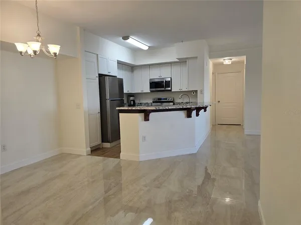 a kitchen with stainless steel appliances a sink a stove a refrigerator cabinets and a dining table