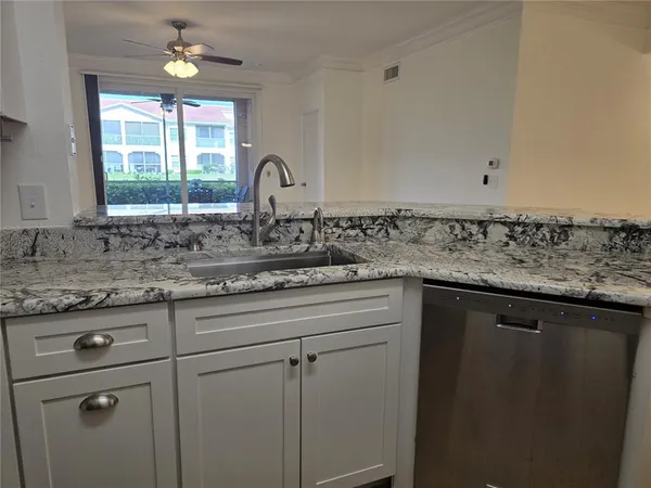 a kitchen with stainless steel appliances granite countertop a sink a window and cabinets