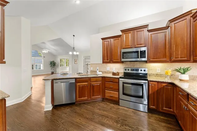 a kitchen with stainless steel appliances granite countertop a lot of counter space and wooden floors