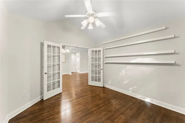 an empty room with a chandelier fan and windows